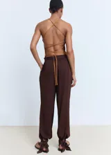 Pantalón estilo globo de color marrón, con diseño abullonado en el bajo, cintura elástica y detalle de lazos ajustables en los tobillos.