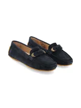 Mocasín de gamuza en color azul marino, con detalle de lazo frontal y herraje metálico dorado. Cuenta con suela de goma color caramelo.