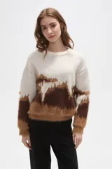Sweater de punto con diseño de bloques de color en tonos crema, marrón oscuro y caramelo. Presenta una textura afelpada, cuello redondo a la base, mangas largas y corte holgado.