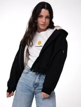 Chaqueta negra de lona de algodón con forro interno de corderito (sherpa), capucha ajustable con cordón y cierre frontal de cremallera metálica. Cuenta con bolsillos laterales y puños y dobladillo de punto acanalado.