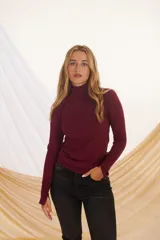 Polera negra de cuello alto y mangas largas con detalle de botones plateados en los puños.