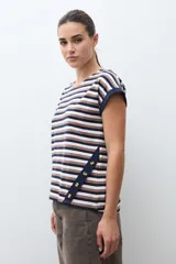 Remera de algodón con estampado de rayas horizontales en tonos azul marino, marrón y blanco. Presenta cuello redondo, mangas cortas con dobladillo y detalle de botones en el lateral inferior.