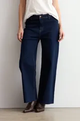 Jean culotte de tiro alto y corte recto, confeccionado en denim de color azul oscuro. Presenta costuras en contraste y un diseño de pierna ancha con ruedo desflecado.