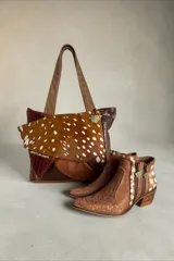 Cartera tipo shopper confeccionada en cuero con diseño patchwork en tonos marrones y animal print, asas de hombro en tono tostado y detalle de dije colgante metálico triangular.