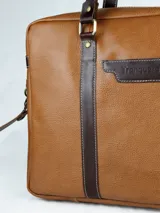 Maletín morral de cuero marrón con doble asa de mano, correa bandolera ajustable y bolsillo frontal. Ideal para laptop. Hecho en Uruguay.