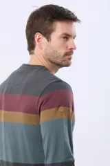 Remera de manga larga con cuello redondo y diseño de rayas horizontales en tonos gris oscuro, bordó, mostaza y verde azulado. Incluye un parche decorativo en la manga.