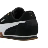 Championes Puma modelo Bella Donna, de diseño urbano y deportivo en color negro con la franja lateral característica en blanco. Presentan una suela de goma color caramelo con excelente tracción y detalles en dorado en los ojales de los cordones.