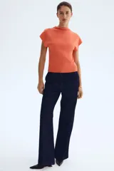 Top en punto fino tupido color naranja con cuello elevado corto y manga japonesa, con remate acanalado en el bajo.