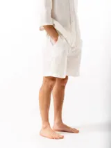 Short de lino con cintura elástica y cordón ajustable. Cuenta con dos bolsillos laterales y un bolsillo trasero, ofreciendo un ajuste cómodo y versátil.