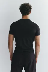 Remera deportiva de compresión color negro, con cuello redondo, mangas raglán cortas y costuras planas antifricción.