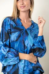 Blusa estampada en tonos de azul, de seda y viscosa, con escote en V y mangas largas terminadas en puño elástico.