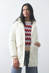 Campera capitoneada de largo medio, color negro, con cuello alto, cierre frontal con cremallera y broches a presión, y bolsillos laterales con solapa.