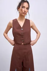 Chaleco corto de corte sastrero en color marrón, con escote en V y cierre frontal con botones a tono.