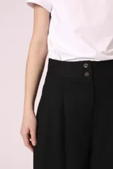 Pantalón palazzo negro con bordado de pequeñas tachas plateadas en forma de rombos a lo largo de la pierna.