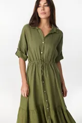 Vestido camisero largo de lino italiano color celeste, de corte relajado, con mangas caídas, jareta ajustable en la cintura, cierre frontal de botones y bajo con volado fruncido.