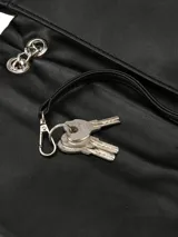 Cartera de hombro color negro con diseño estructurado, solapa frontal y detalle de cadena metálica plateada. Incluye correa ajustable y logo de la marca en la parte frontal.