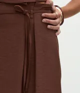 Pollera midi de corte sastre color bordó, con cintura estructurada, trabillas y lazo delantero ajustable en cordón del mismo tono.
