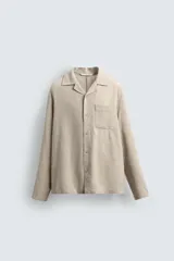Camisa de corte relajado confeccionada en una mezcla de lyocell y lino. Presenta cuello bowling, manga larga con puño abotonado, bolsillo de plastrón en el pecho y cierre frontal con botones.