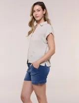 Camisa de lino de estructura recta, color beige con rayas verticales blancas. Cuenta con cuello solapa, escote en V abierto, abotonadura frontal, bolsillo plaqué en el pecho, mangas cortas de hombro caído y ruedo recto.