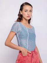 Top de mangas cortas con estampado geométrico en tonos verde y amarillo, con transparencias y costuras a la vista.