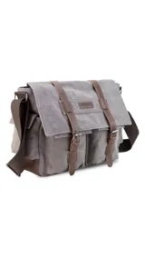 Morral de tela canvas color gris con detalles en cuero marrón, con tapa y doble bolsillo frontal, trasero y laterales. Interior espacioso con compartimento para notebook de 15". Correa de galón regulable para mayor comodidad.