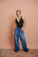 Pantalón de jean celeste de corte recto, con detalles de apliques desflecados en los bolsillos delanteros y roturas en la pierna.