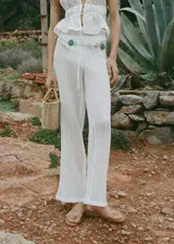 Pantalón de corte recto y tiro medio, confeccionado en una mezcla de ramio y algodón con textura arrugada. Presenta cintura elástica con lazo ajustable y diseño largo.