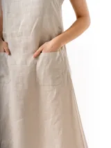 Vestido largo de lino color beige, con breteles finos regulables, escote recto, bolsillos laterales y tajo lateral.