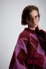 Jersey de punto de lana con diseño de rombos en tonos bordó y lila. Presenta cuello redondo, manga larga con puños ajustados y corte holgado.