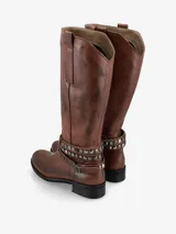 Bota de caña alta confeccionada en cuero negro, con punta redondeada y taco bajo. Presenta correas decorativas alrededor del tobillo con tachas metálicas y hebilla de ajuste, además de tiradores laterales en la parte superior.