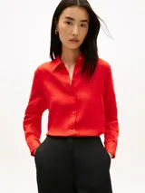 Camisa de corte amplio confeccionada en lino puro, de color rojo, con cuello inglés, mangas largas con puños abotonados, bajo camisero y cierre frontal de botones. Cuenta con el logo de Tommy Hilfiger bordado en el pecho.