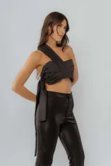 Top de un solo hombro con diseño fruncido y lazo lateral para anudar. Presenta una estructura cruzada en el frente y espalda descubierta.