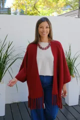 Saco abierto tipo capa en color bordó, confeccionado en tejido de punto suave, con mangas amplias y detalle de flecos en el ruedo.