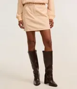 Minifalda color beige confeccionada en terciopelo cotelé, de cintura alta y corte recto.