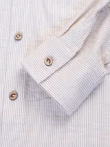 Camisa celeste a rayas verticales blancas, de manga larga con botones de madera y parche con logo de la marca en el ruedo.