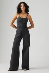 Mono largo de denim negro con corte bustier, tirantes finos y cierre frontal con cremallera.