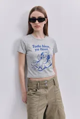 Remera corta gris melange con estampa frontal en color azul de un perro y la frase "Todo bien, ya lloré", de manga corta y cuello redondo.