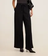 Pantalón de corte recto y estilo sastre, confeccionado en una mezcla de poliéster y viscosa. Presenta cintura alta con elástico y lazo ajustable, costuras frontales decorativas y bolsillos laterales.