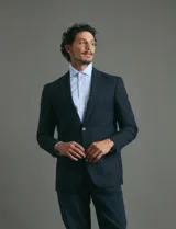 Saco de vestir azul oscuro con textura sutil, corte entallado, cierre frontal de un botón y solapas clásicas.