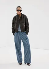 Pantalón estilo tejano vaquero de algodón con diseño largo y recto, tiro medio y estampado de rayas. Cuenta con dos bolsillos laterales y cierre de lazo en la cintura.