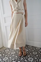 Sandalia plana de color negro con textura efecto piel de serpiente. Presenta una tira central con un aplique metálico dorado curvo y cierre de pulsera con hebilla ajustable en el tobillo.