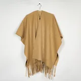 Ruana de tejido suave en color beige, con diseño abierto y terminación de flecos en el ruedo.