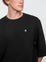 Remera de corte oversized en color beige claro, con cuello redondo y mangas de largo medio. Presenta un pequeño bordado del oso Brannan de Gap en el lado izquierdo del pecho.