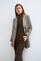 Saco corto entallado de lana fina, con cuello solapa, manga larga y cierre frontal con botones. Presenta un diseño clásico con textura de espiga en tonos tierra.