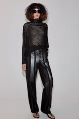 Camisa de hilatura con viscosa color negro, con cuello subido y manga larga ancha. Presenta aplicaciones de abalorios combinados a tono en toda la prenda y bajo recto.