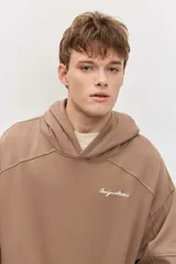 Canguro marrón con capucha, bolsillo frontal tipo kango y diseño oversize de corte relajado con mangas largas.