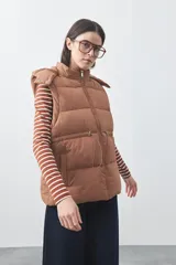 Chaleco puffer negro con diseño acolchado, capucha desmontable y cierre frontal. Cuenta con cordones ajustables en la cintura y bolsillos laterales.
