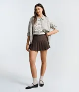 Short pollera de estilo sastre en color marrón, con diseño de pliegues estructurados, cintura con trabillas y cinturón fino ajustable incluido.