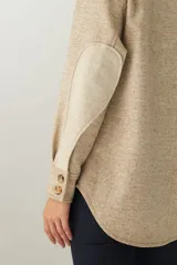 Camisa estilo leñador color beige con textura en espiga, de manga larga, con cuello clásico, cierre frontal con botones, dos bolsillos de parche con solapa abotonada en el pecho y puños abotonados. Confeccionada en lana fina sin teñir.