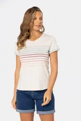 Remera de manga corta con cuello redondo, color base crema, con rayas horizontales en tonos pastel como rosado, azul claro y verde pálido. Los puños de las mangas son doblados y tienen un borde de color celeste pálido.